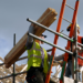 Man carrying wood planks on scaffolding.